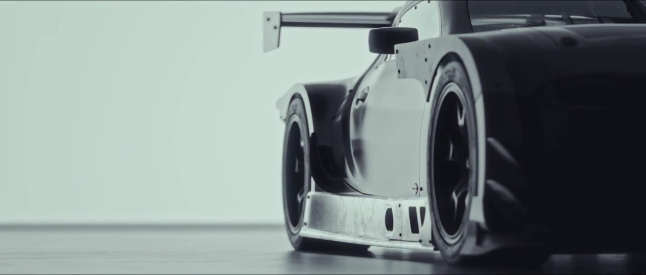A ground-level three-quarter view of a race car on a high-key white ground.